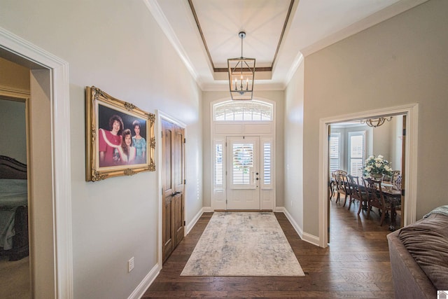 entrance foyer with dark wood-style floors, ornamental molding, and a healthy amount of sunlight