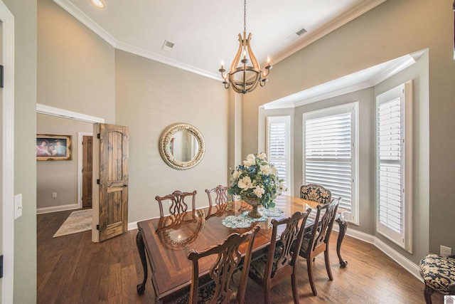 dining room with dark wood-type flooring, an inviting chandelier, visible vents, and crown molding