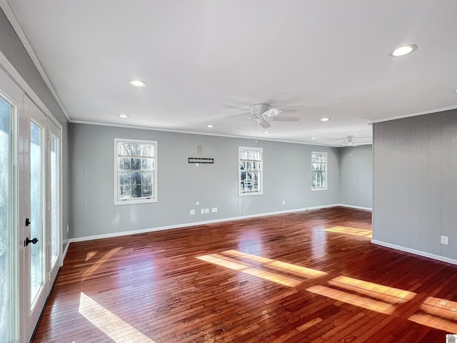 spare room with dark wood-style floors, baseboards, ornamental molding, and a ceiling fan