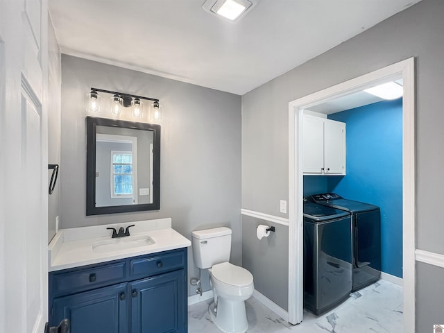 half bathroom featuring marble finish floor, toilet, vanity, washer and dryer, and baseboards