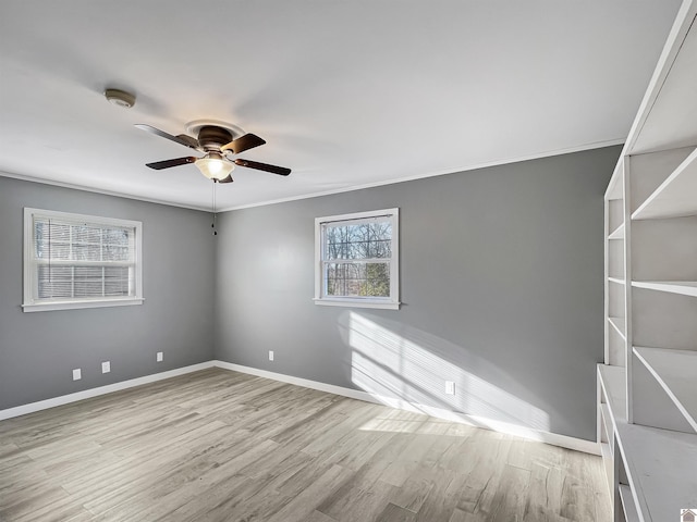 empty room featuring light wood finished floors, a ceiling fan, baseboards, and crown molding