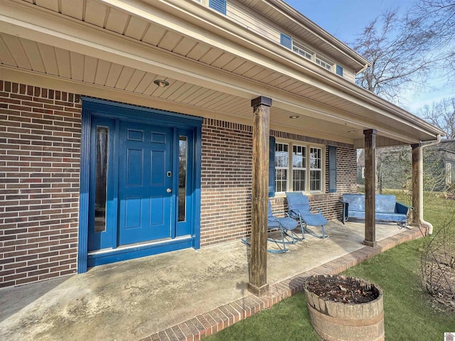 view of exterior entry featuring a patio area and brick siding