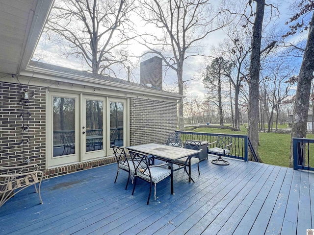 wooden terrace featuring outdoor dining space and a yard