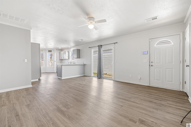 unfurnished living room with visible vents, ceiling fan, a textured ceiling, and wood finished floors