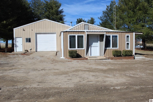 view of front of house with board and batten siding, driveway, and a detached garage