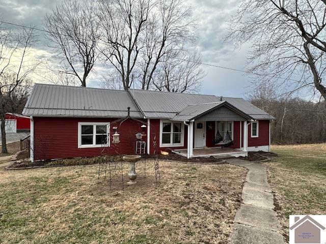 ranch-style home featuring a porch, metal roof, and a front lawn