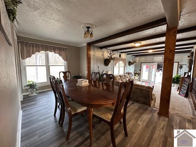 dining area featuring beamed ceiling, a textured ceiling, and wood finished floors