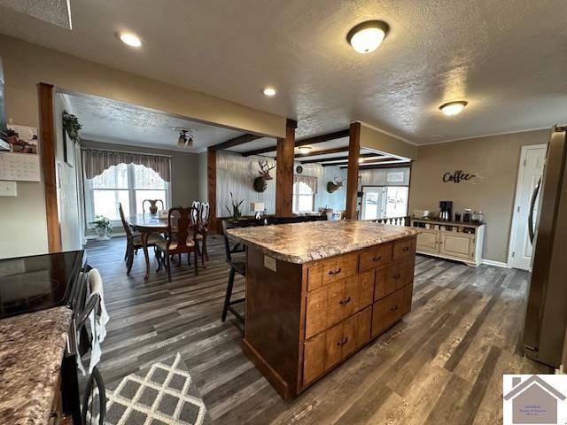 kitchen with dark wood-style floors, freestanding refrigerator, range with electric stovetop, and a textured ceiling