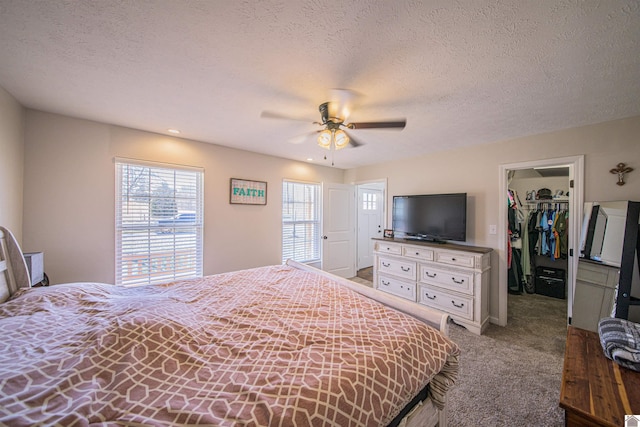 bedroom featuring ceiling fan, a textured ceiling, carpet flooring, a spacious closet, and a closet