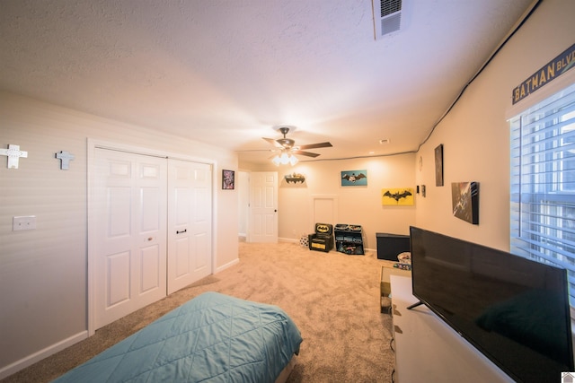 carpeted bedroom with a closet, visible vents, a textured ceiling, and baseboards