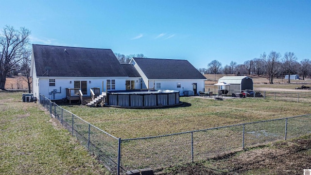 back of house featuring a fenced in pool, cooling unit, a lawn, and fence