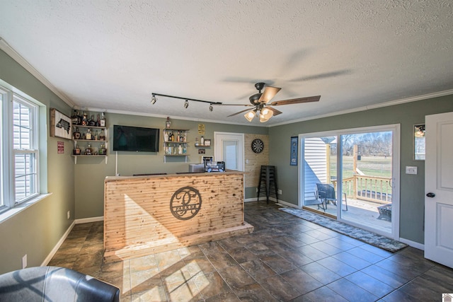 interior space featuring a textured ceiling, ceiling fan, ornamental molding, and baseboards