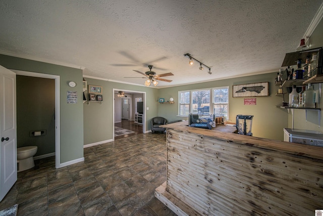 bar featuring a textured ceiling, ceiling fan, baseboards, and crown molding