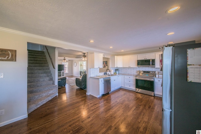 kitchen with white cabinets, dark wood-style floors, appliances with stainless steel finishes, a sink, and backsplash