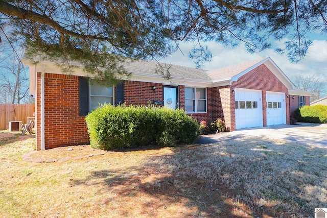 single story home with a garage, driveway, brick siding, fence, and a front yard