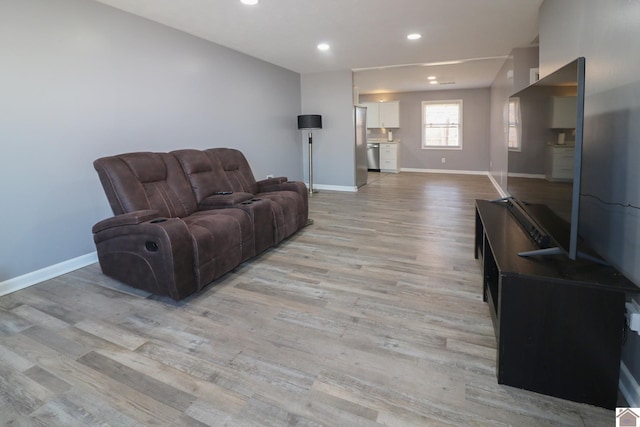 living area with light wood-style flooring, baseboards, and recessed lighting