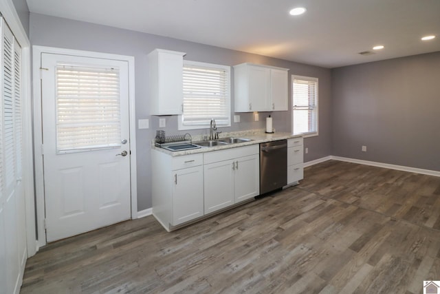 kitchen with dark wood-style floors, stainless steel dishwasher, a sink, and white cabinetry