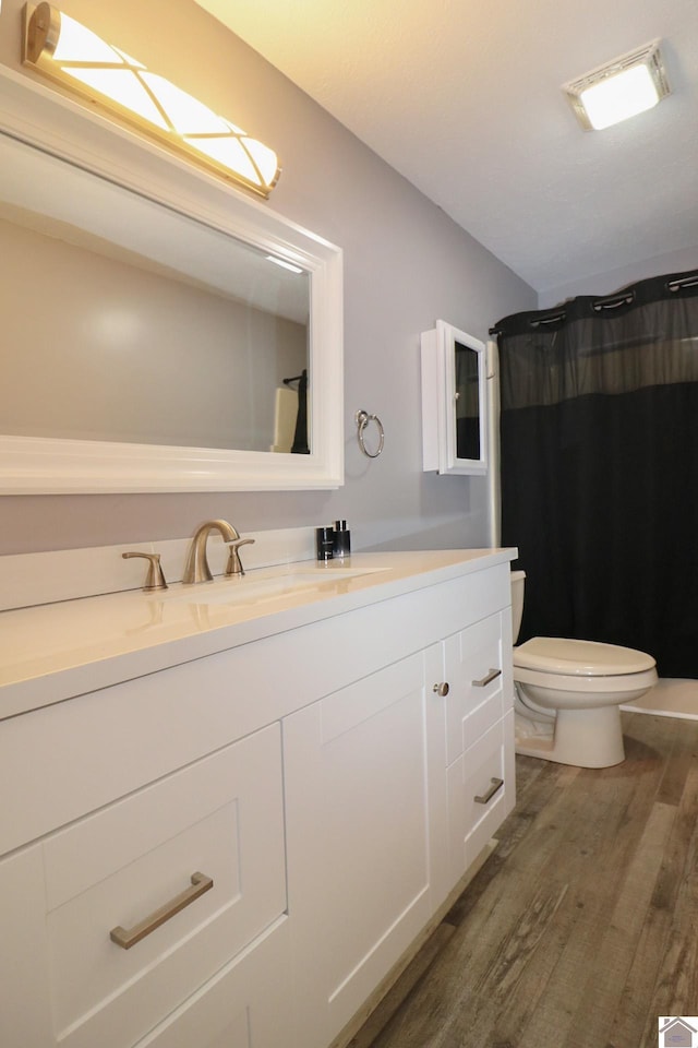 full bathroom with toilet, a shower with curtain, wood finished floors, and vanity