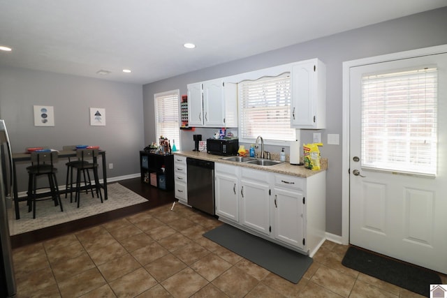 kitchen with black microwave, light countertops, stainless steel dishwasher, white cabinetry, and a sink