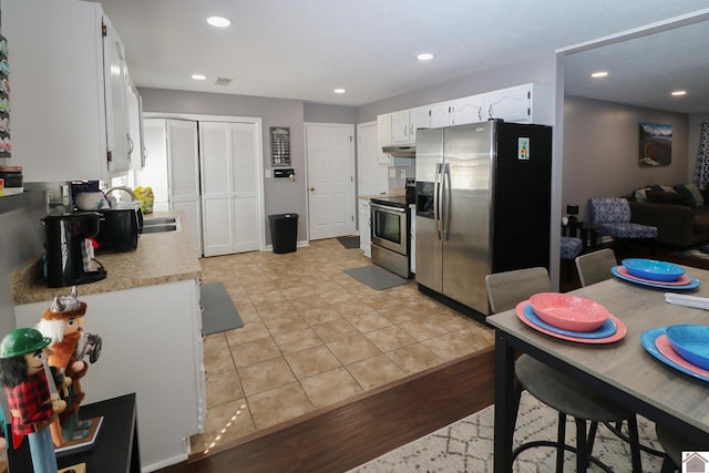 kitchen with light tile patterned floors, recessed lighting, white cabinets, light countertops, and appliances with stainless steel finishes