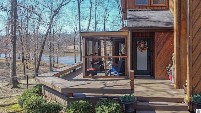 wooden deck with a water view, fence, and a sunroom