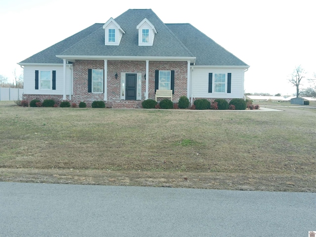 view of front facade with brick siding, a front lawn, and a shingled roof