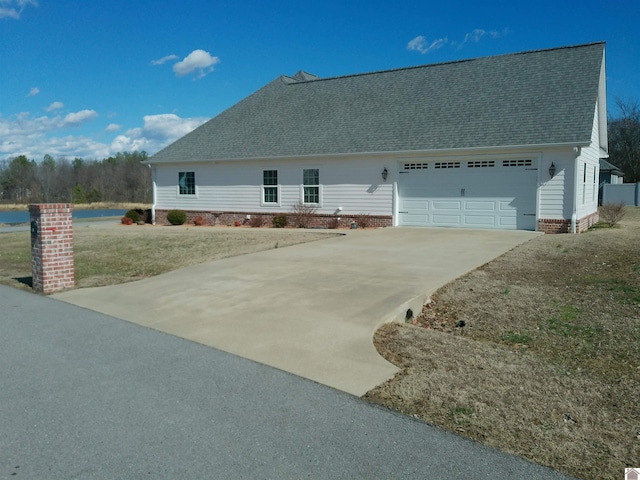 view of front of home with driveway, a shingled roof, and a garage