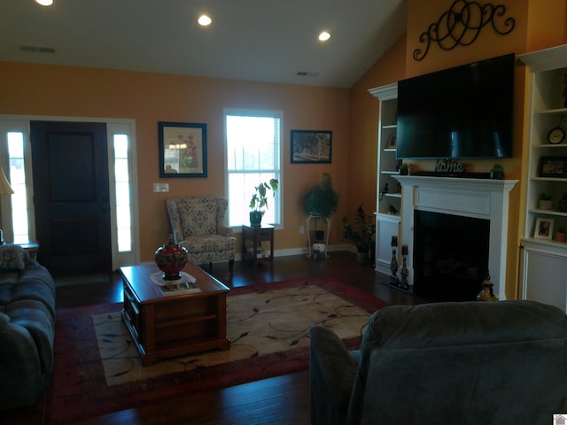 living area featuring vaulted ceiling, wood finished floors, a fireplace with flush hearth, and visible vents