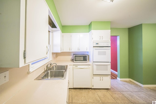 kitchen featuring light tile patterned floors, white appliances, a sink, white cabinets, and light countertops