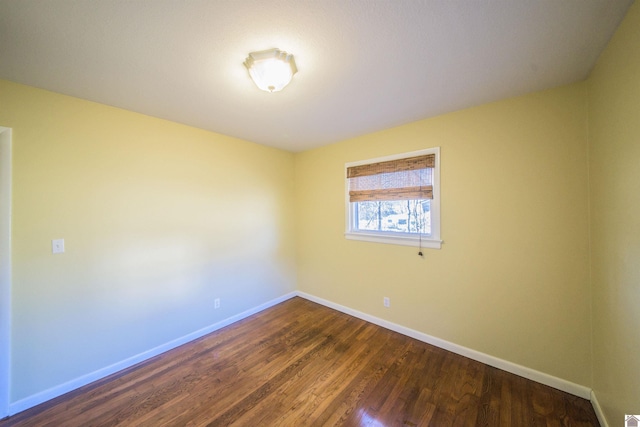 unfurnished room featuring dark wood-style flooring and baseboards