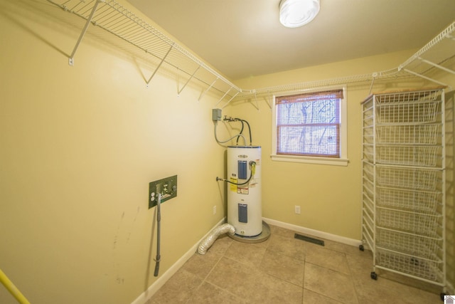 laundry room featuring tile patterned flooring, electric water heater, visible vents, and baseboards