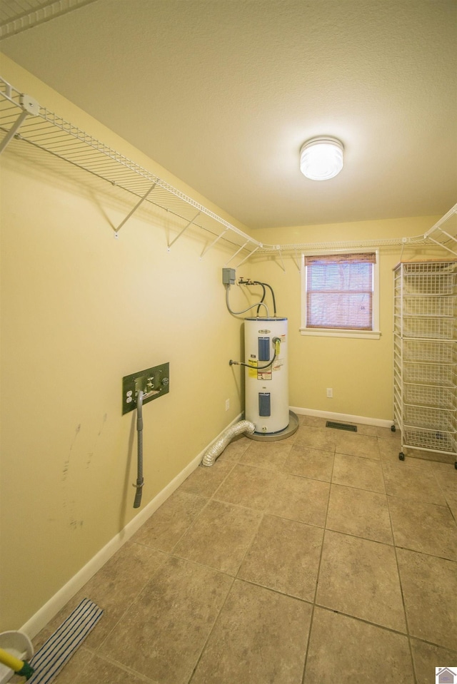 laundry room with laundry area, visible vents, baseboards, tile patterned floors, and electric water heater