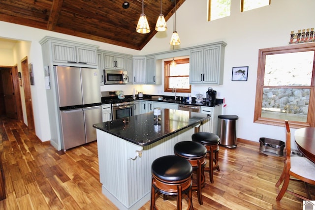 kitchen featuring light wood finished floors, wood ceiling, appliances with stainless steel finishes, and pendant lighting