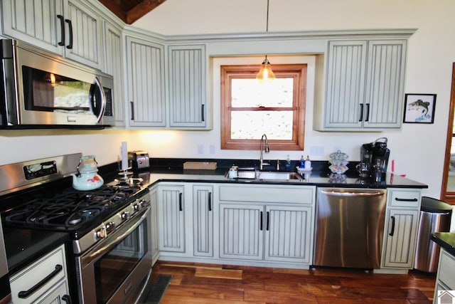 kitchen with dark countertops, dark wood-style floors, stainless steel appliances, and a sink