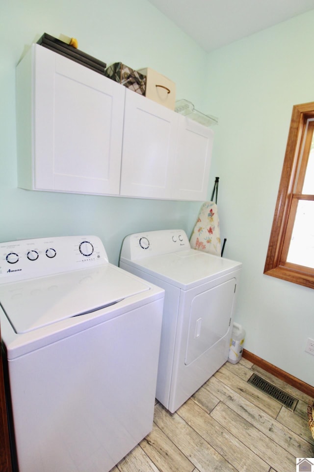 laundry room with separate washer and dryer, visible vents, baseboards, cabinet space, and light wood finished floors