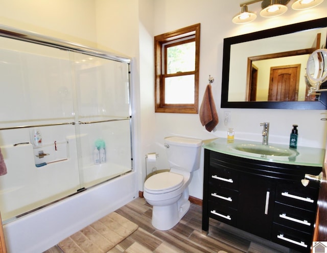 bathroom featuring shower / bath combination with glass door, toilet, vanity, wood finished floors, and baseboards