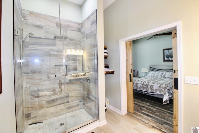 ensuite bathroom with ensuite bathroom, wood finished floors, a shower stall, and baseboards