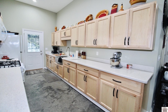 kitchen with white appliances, light countertops, a sink, and light brown cabinetry