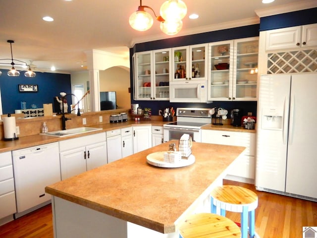 kitchen with crown molding, white appliances, wood finished floors, and white cabinets