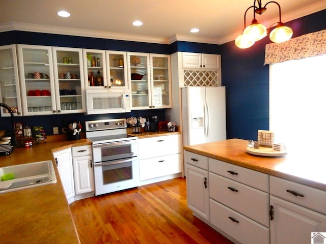 kitchen featuring white appliances, white cabinets, light wood-type flooring, glass insert cabinets, and crown molding