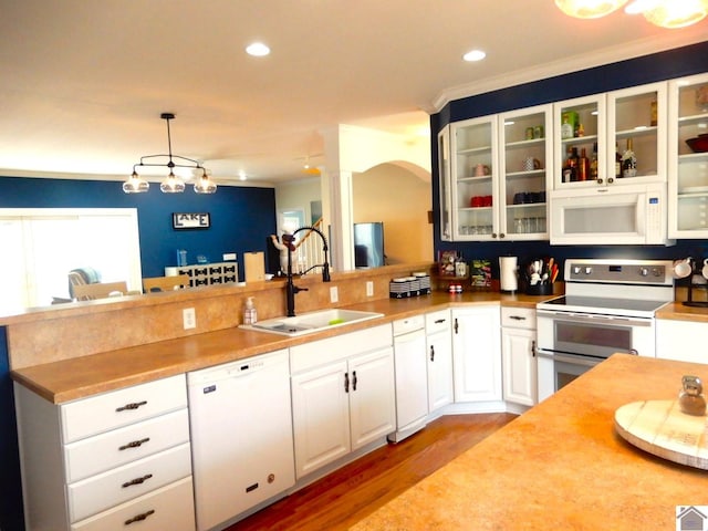 kitchen featuring white appliances, white cabinetry, a sink, and a peninsula