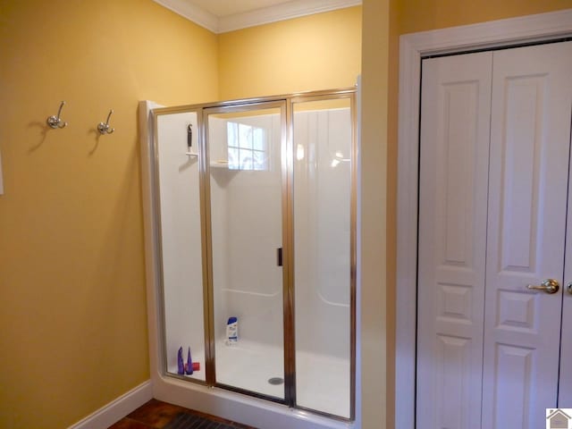 full bathroom featuring a stall shower, a closet, crown molding, and baseboards