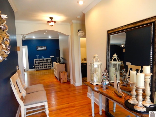 corridor with arched walkways, baseboards, wood finished floors, and crown molding