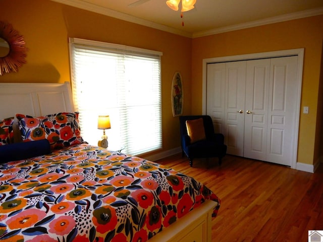 bedroom with crown molding, a closet, a ceiling fan, light wood-type flooring, and baseboards