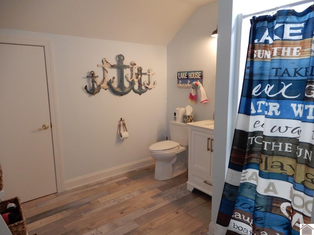 bathroom with baseboards, toilet, hardwood / wood-style flooring, a shower with curtain, and vaulted ceiling