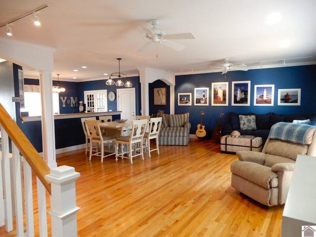 living room with crown molding, wood finished floors, a ceiling fan, stairway, and track lighting