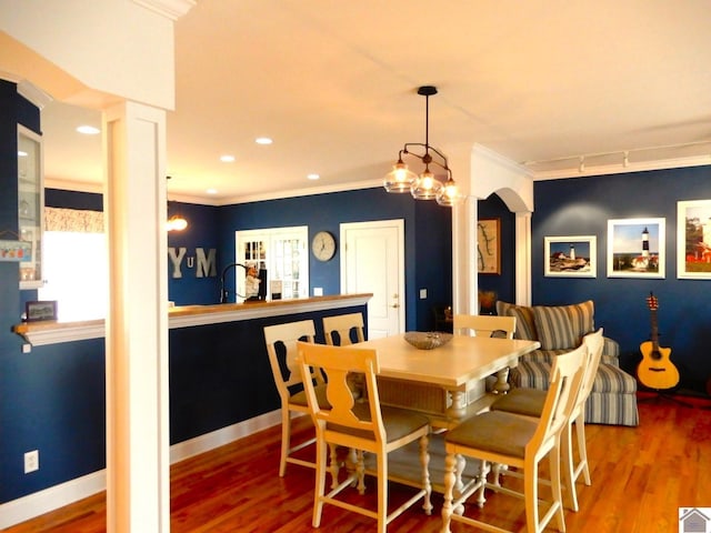 dining room with decorative columns, crown molding, and wood finished floors