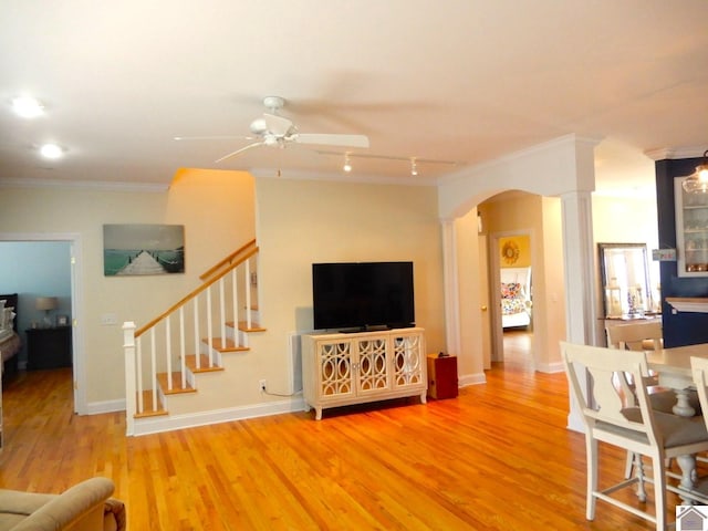 living area featuring arched walkways, ornamental molding, stairway, and wood finished floors