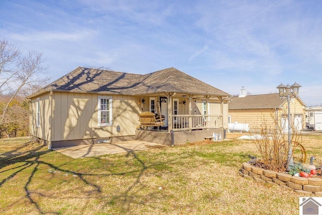 rear view of property featuring a patio area, roof with shingles, and a lawn