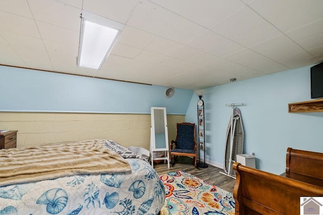 bedroom with concrete block wall and wood finished floors